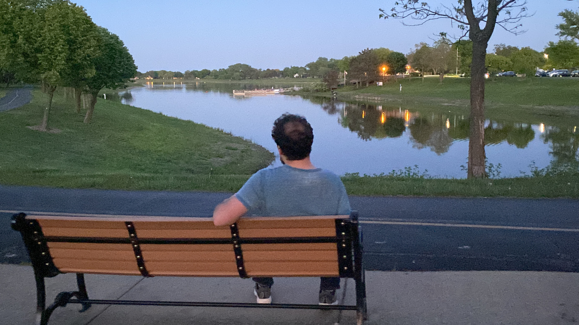 Elliott sitting on a bench looking out over a lake at dusk